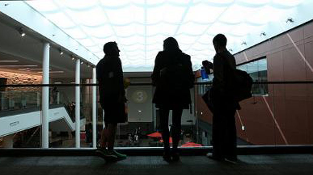 Three students looking over the lower level at the Damen Student Center